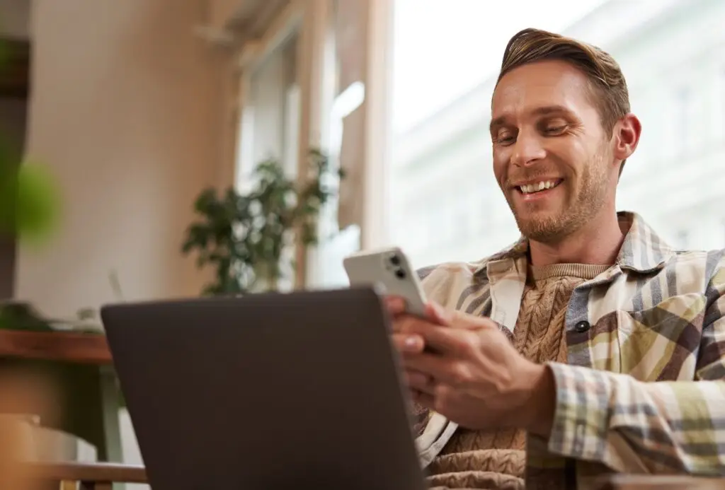 Hombre revisando en su celular el pago puntual de su apartamento en administración con Efectibienes, inmobiliaria en Medellín
